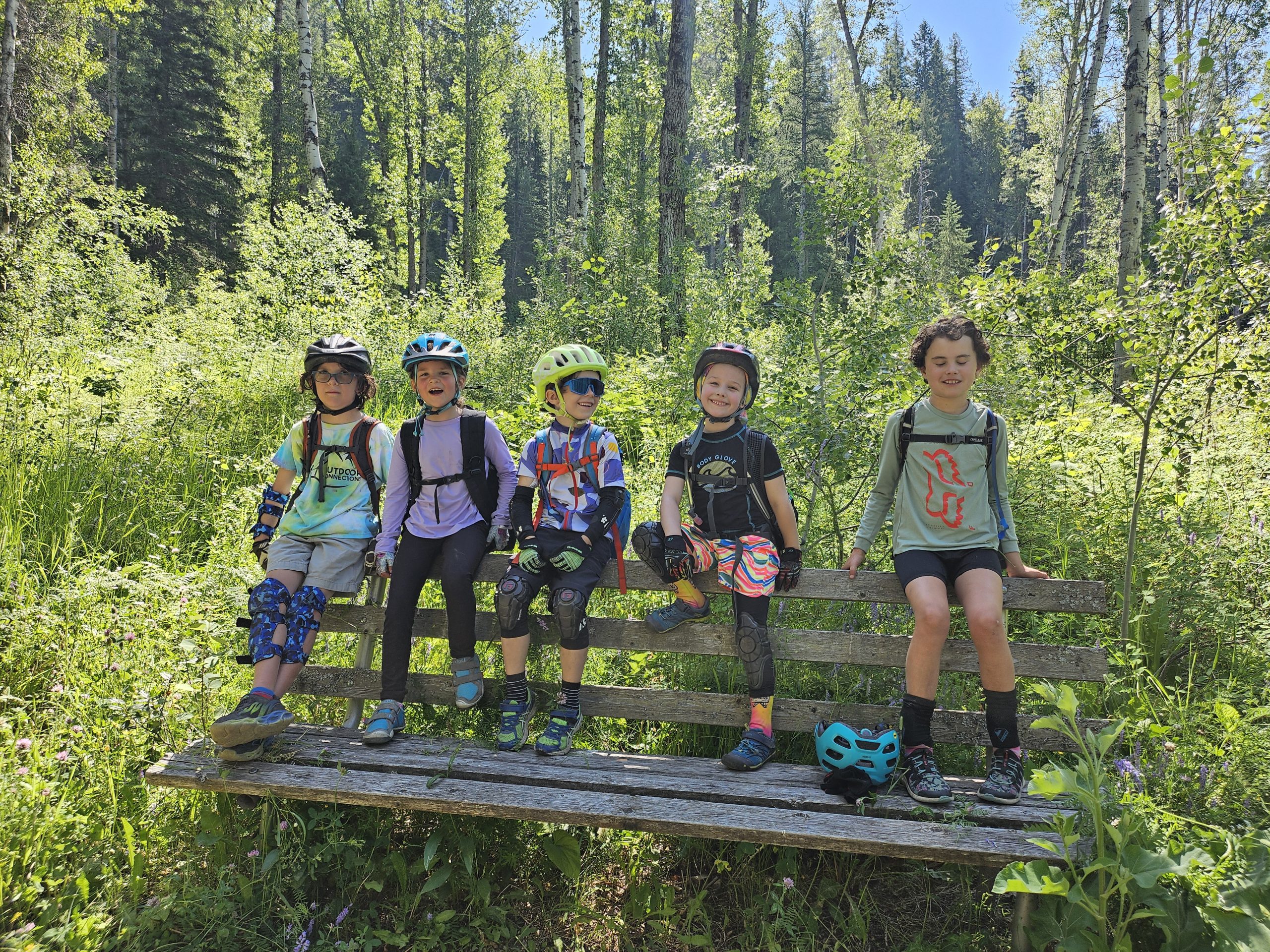 kids sitting on a bench taking a break from bikinf